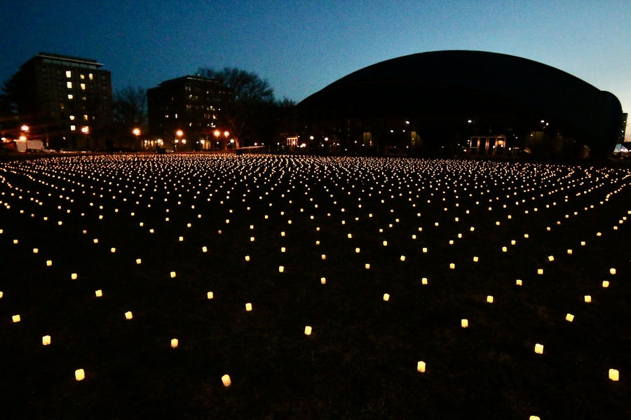 Photo of Kresge Oval at night with lit battery-operated candles displayed in rows.