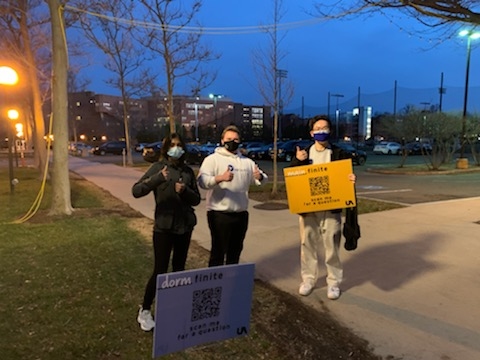 Photo of three members of The _finite team outdoors at night, giving thumbs-up