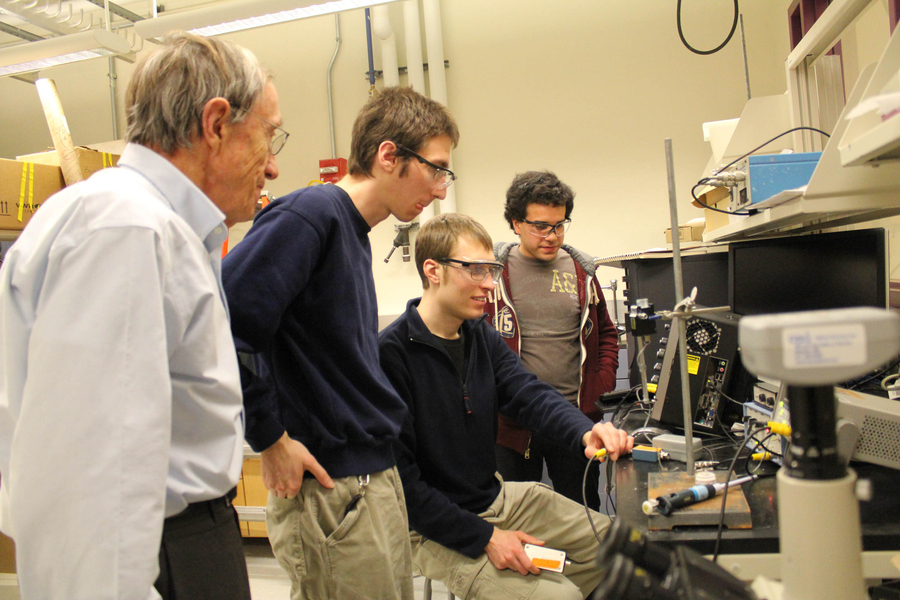 Photo of students centered around a computer screen in a laboratory