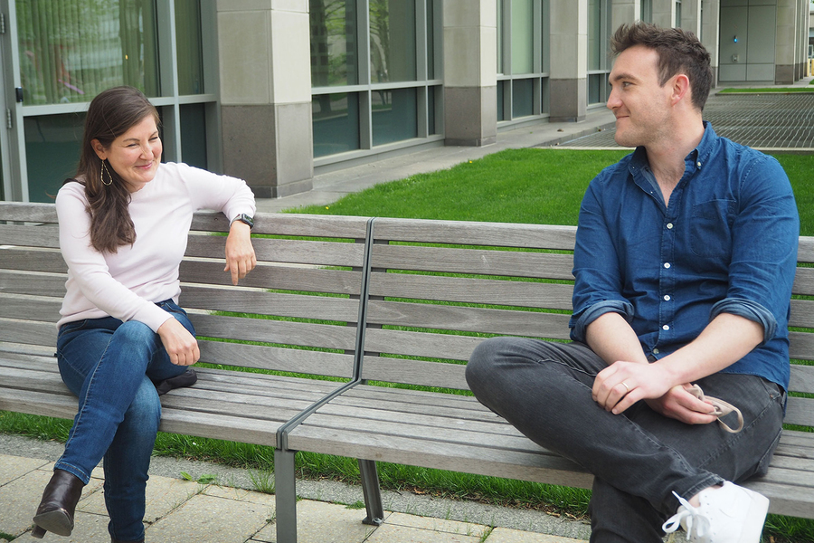 Photo of Laurie Boyer (left) and Alex Auld sitting on a bench outside of an MIT building