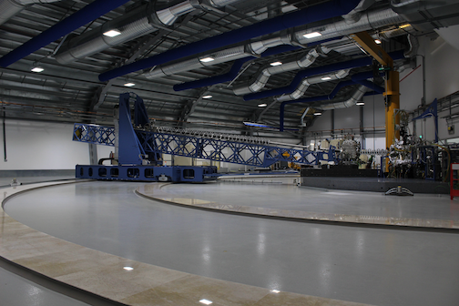 Large linear instrument inside what looks like a warehouse facility, on a circular track