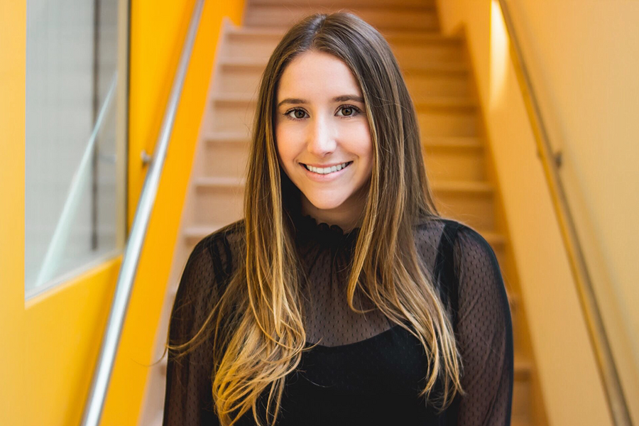 Portrait photo of Gabrielle Finear smiling in front of a yellow stairwell