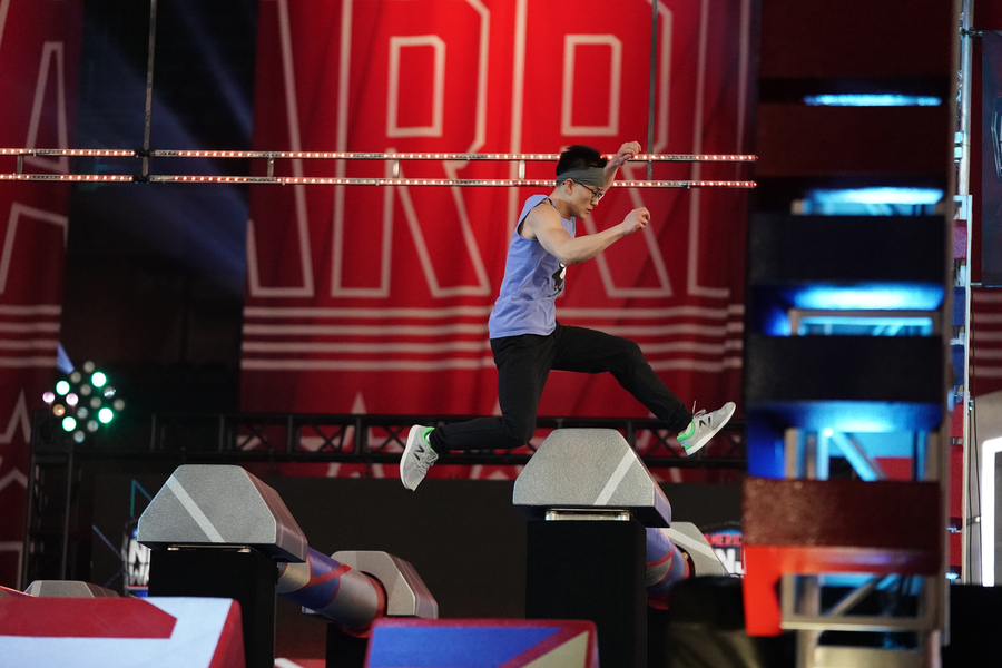 Guang Cui leaps over a series of obstacles on a televised set.
