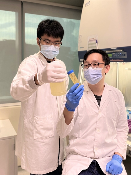 Photo of two men in lab coats, facemasks, and safety glasses examining water samples