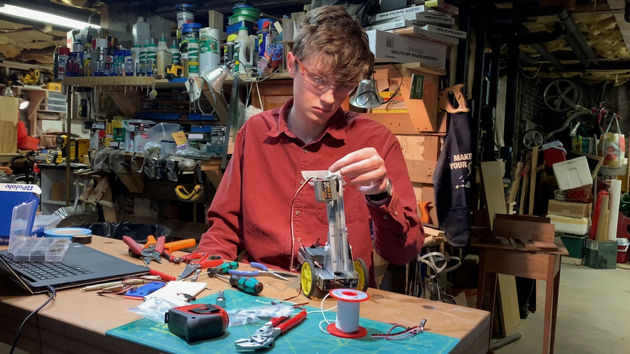 Photo of Satchel Sieniewicz building a robot in his basement