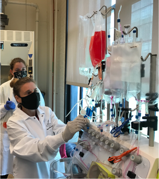 Photo of a professor and a student in white lab coats, working in a lab with flexible liquid tubes and other equipment