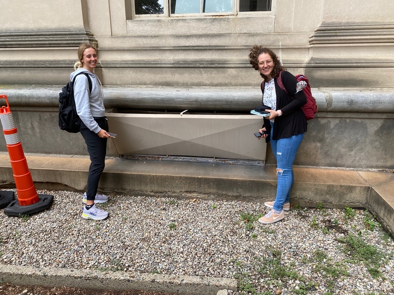 Photo of two women taking measurements outside of building vent