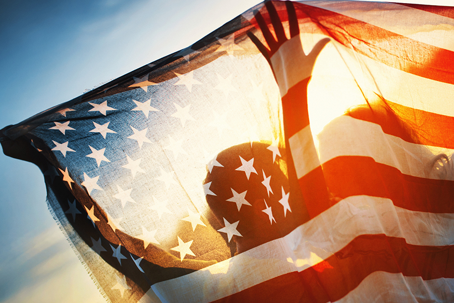 Photo of people holding up U.S. flag illuminated by sunlight