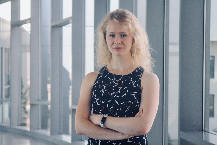 Photo of Mariya Greenberg, standing in front of a window with her arms crossed