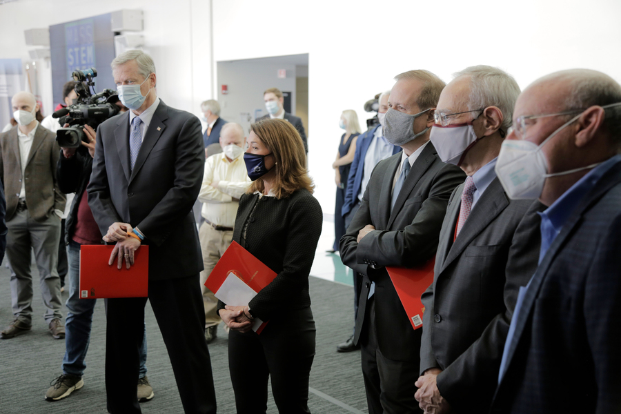 Photo of five people in suits and masks standing in a semi-circle