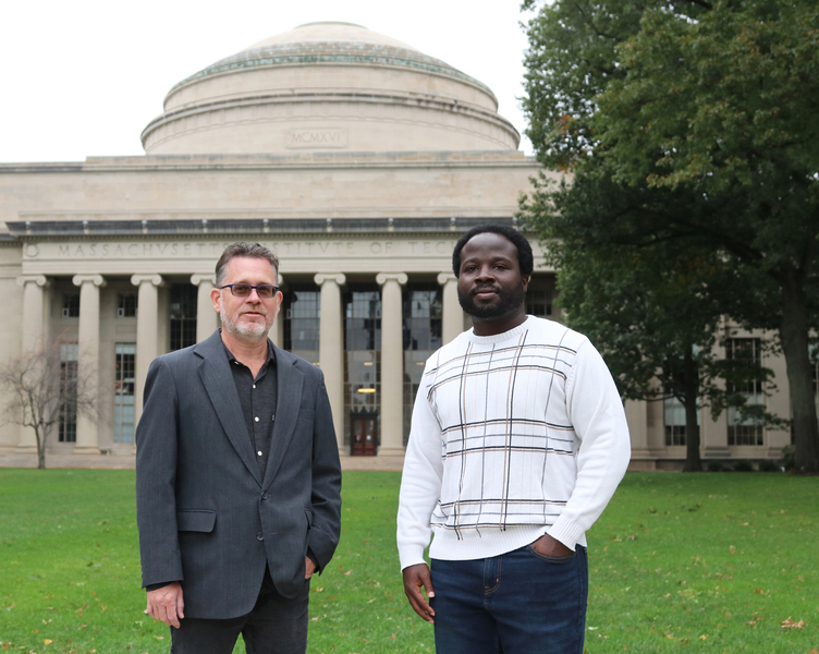 Photo of two men standing in front of MIT’s Great Dome, each with a hand in his pocket.
