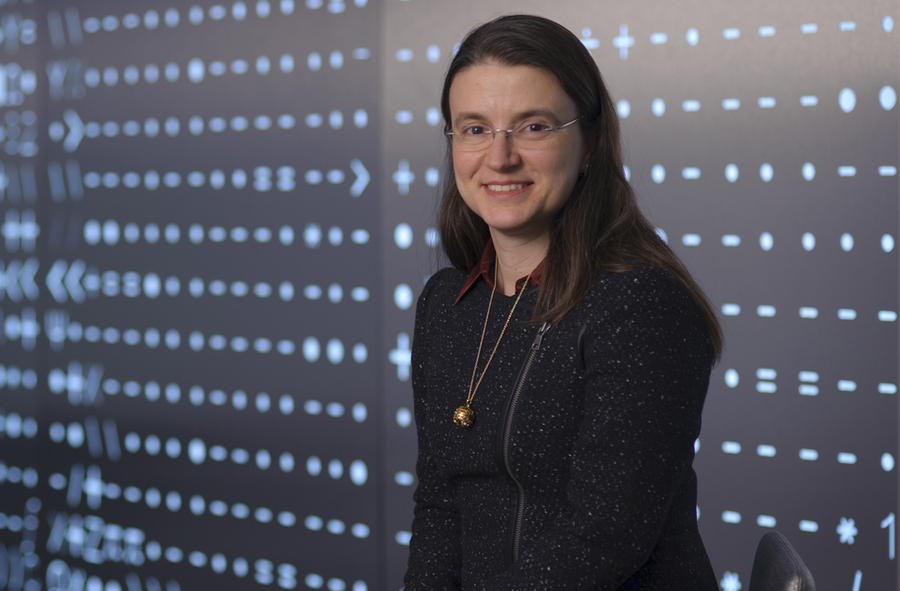 Portrait photo of Bilge Yildiz standing before a background of mathematical symbols