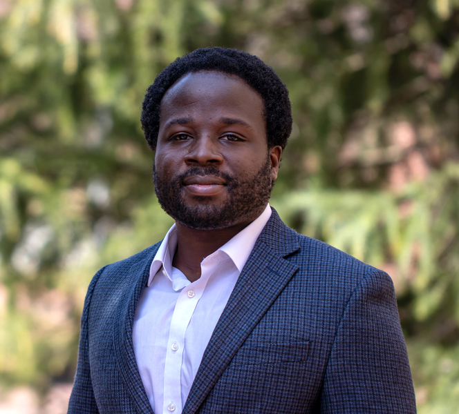 Portrait headshot of Robert Gilliard standing in front of pine trees