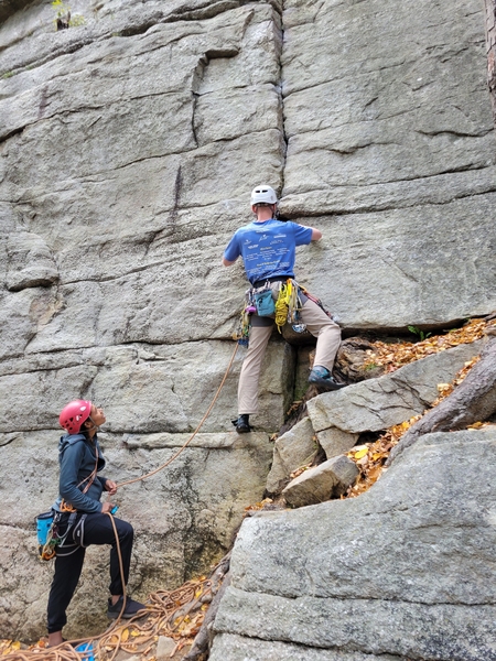Photo of rock climbers using a rope to aid in climbing cliff.