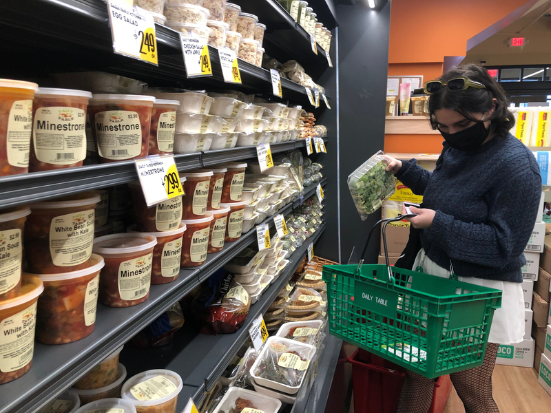 Photo of a student in Daily Table holding basket of grocery items.