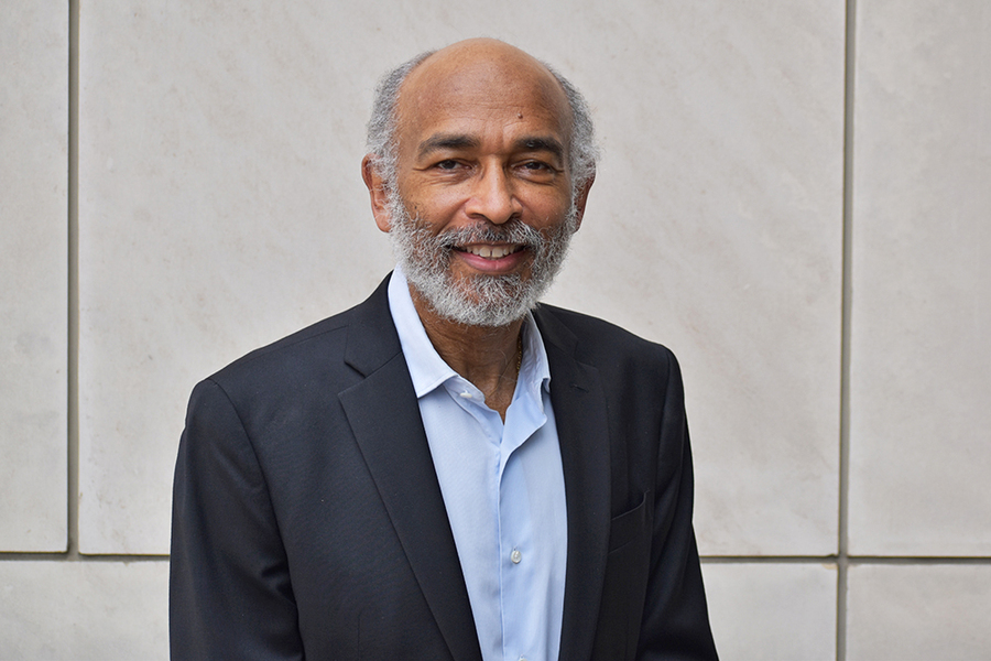 Portrait photo of Emery Brown standing in front of a white stone-covered wall