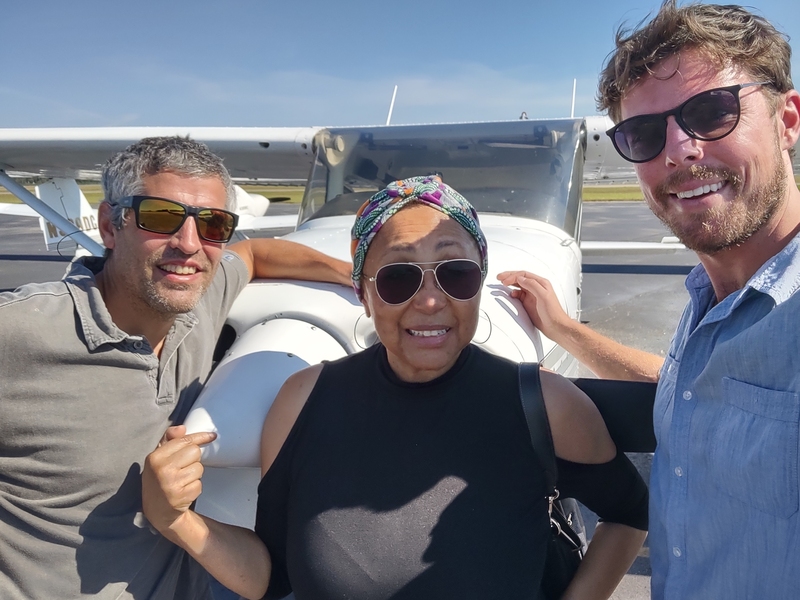 Photo of ESI Journalism Fellow Melba Newsome flanked by two men, all standing in front of a small airplane