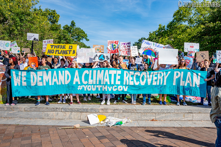 Photo of a large group of young protesters holding a banner reading “We demand a climate recovery plan"