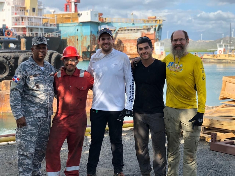 Photo of five men lined up on a dock, smiling at the camera