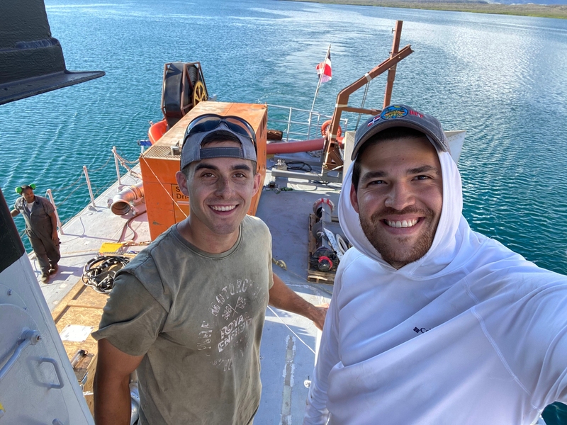 Photo of two men on a boat, smiling at the camera