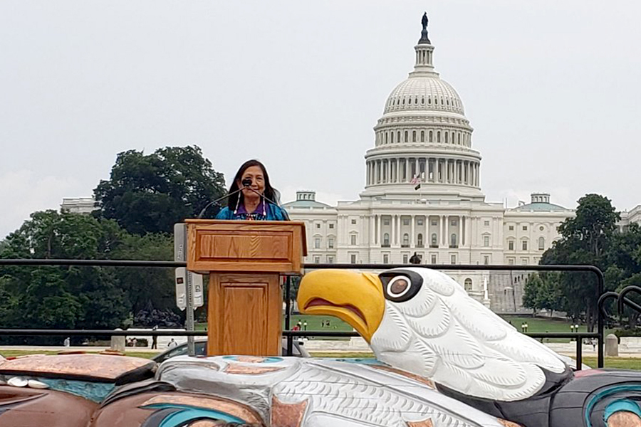 photograph of U.S. Secretary Deb Haaland receiving the Sacred Lands totem pole
