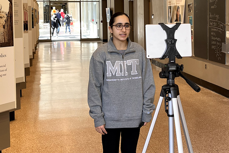 Photo of MIT student Jupneed Singh standing in an MIT hallway in front of a tripod that holds a digital tablet