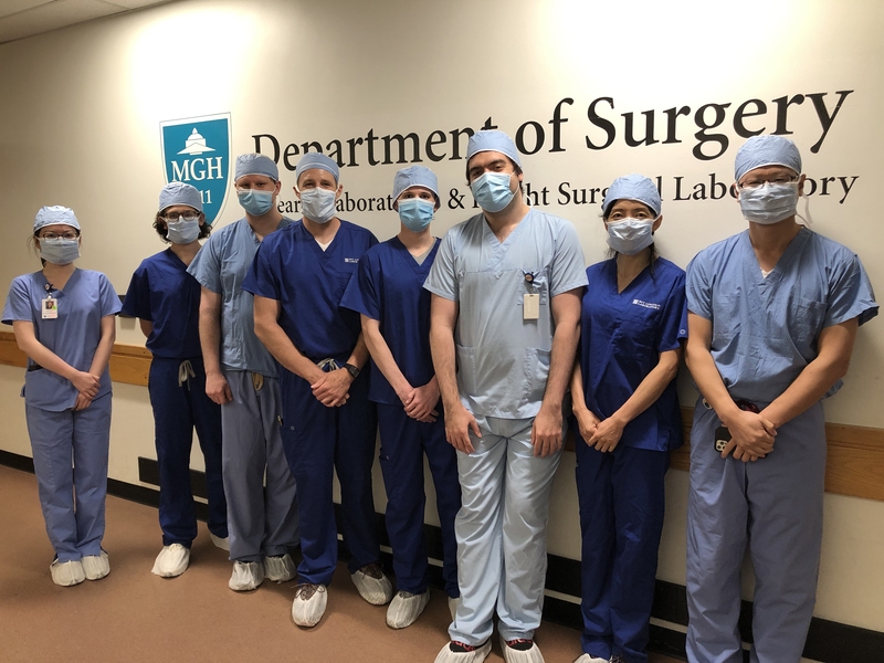 A group of eight surgeons poses for a team photo in front of a wall that says "Department of Surgery" at the Massachusetts General Hospital