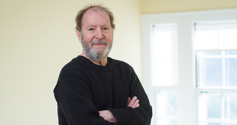Portrait photo of Martin Greenwald, standing with his arms folded in front of a window