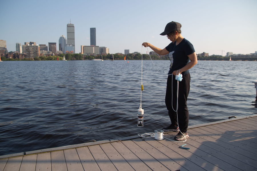 Photo of Charlene Xia pulling a device out of the Charles River