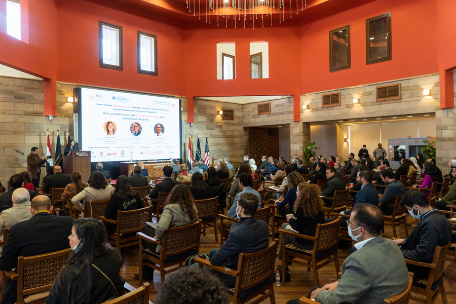 Photo of a seated audience watching a presentation by a speaker at a podium