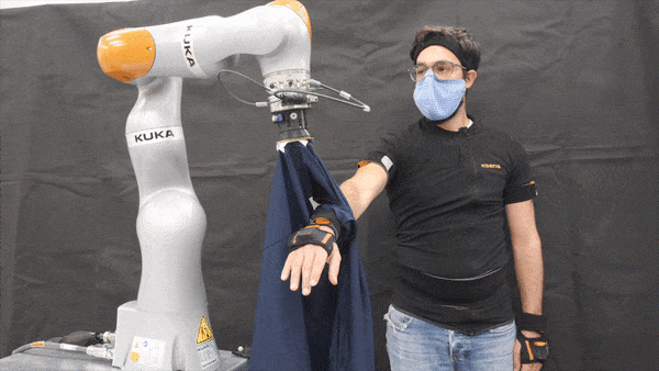 A robotic arm helps put a jacket sleeve on a man