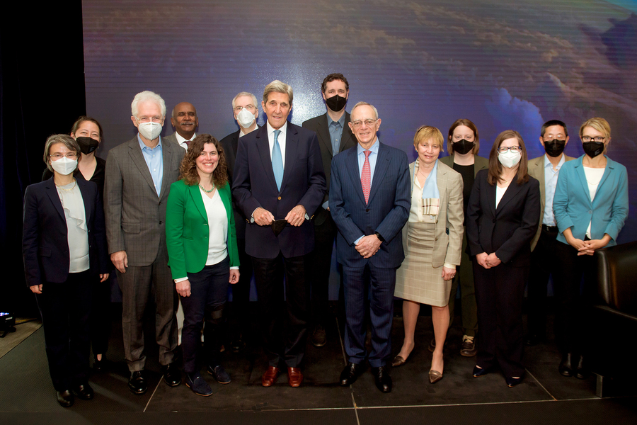 A group of 14 people standing close together, looking at the camera and smiling