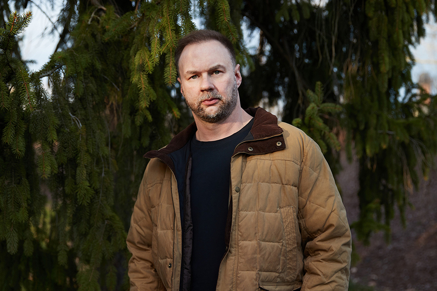 Thomas Tull stands in front of an evergreen tree