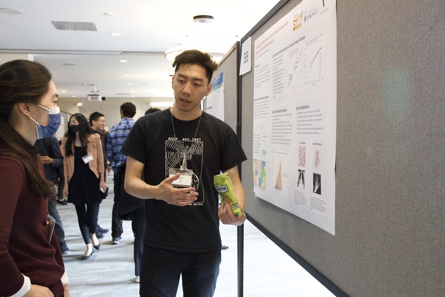 Photo of Nathan Ng explaining his poster to a conference attendee