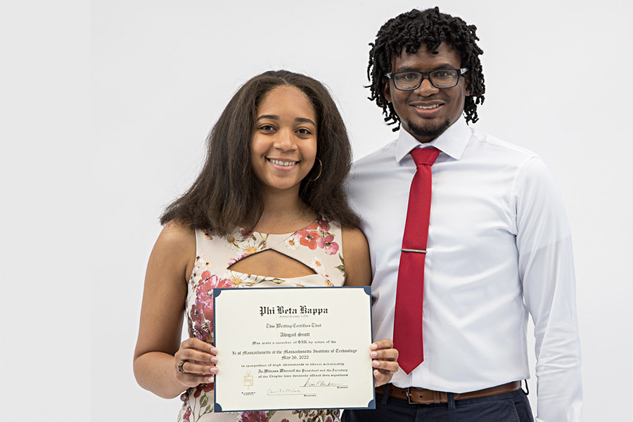 Photo of Abigail Scott standing with another individual and showing off her Phi Beta Kappa certificate