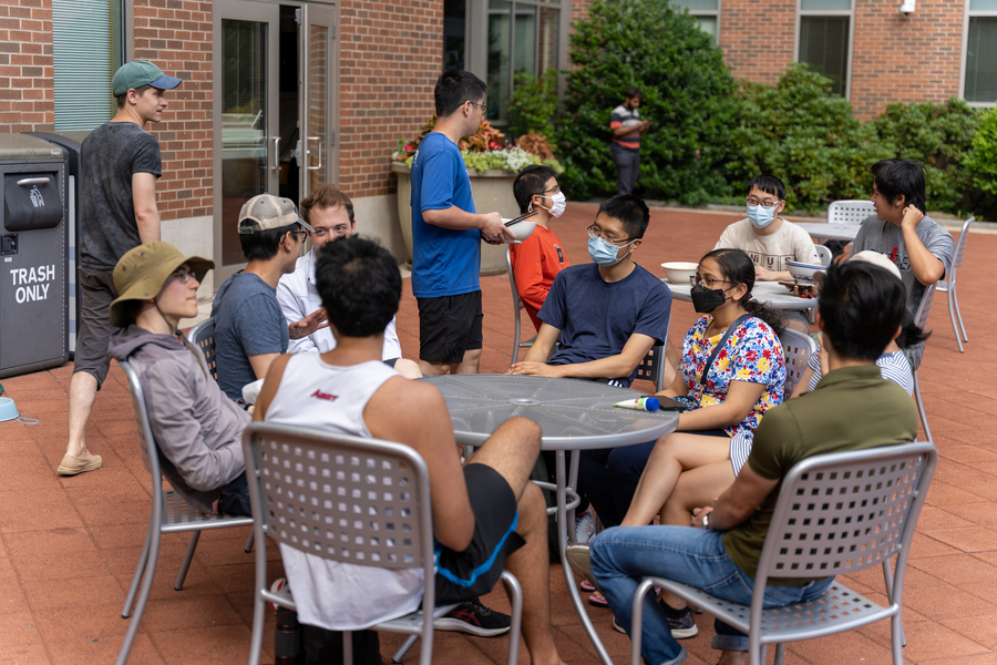 Photo of students sitting at tables on a patio outside Sidney-Pacific hall in summertime