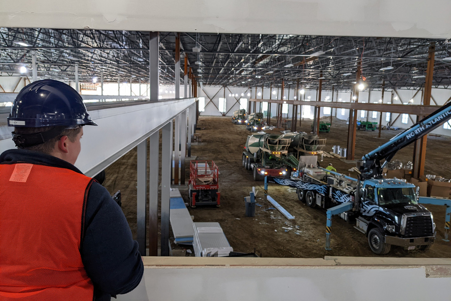 Joy Dunn wearing a hard hat and orange vest, inside a large building being constructed.