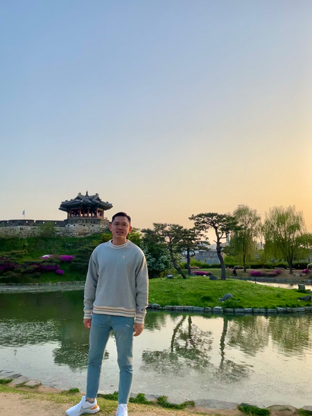 Casually dressed Jung Jae Kwon posing for a photo in front of an Asian landscape