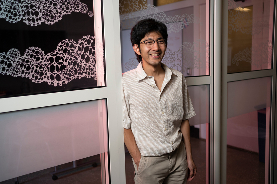 Pablo Leon stands in a doorway with decals on windows.