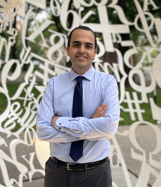 Portrait photo of Mohammad Khojasteh, standing inside a sculpture that surrounds him with white numbers and mathematical symbols