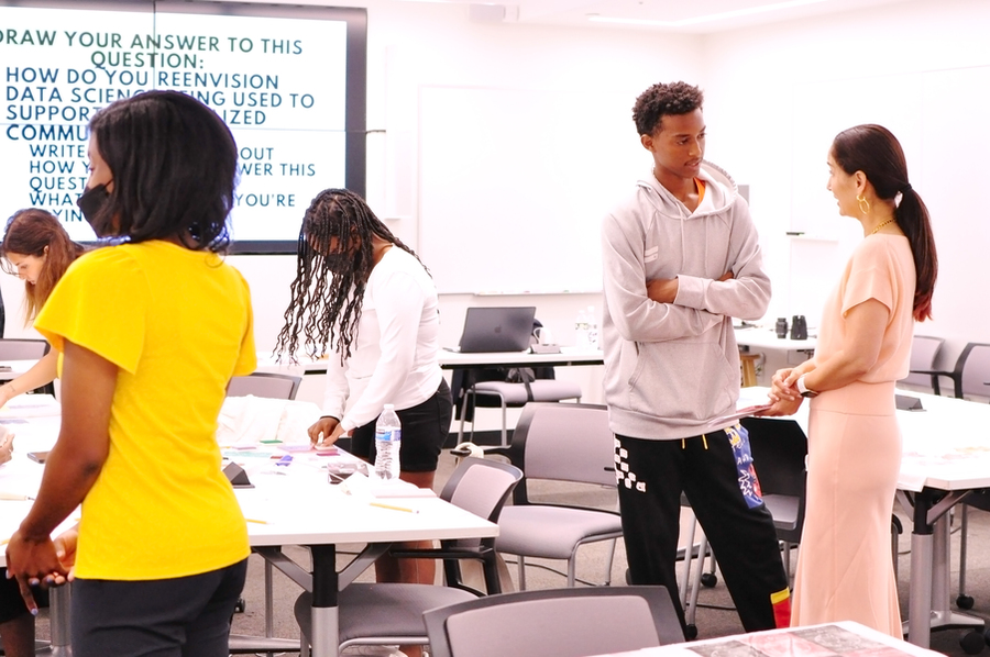 Photo of an MIT classroom with a screen on the wall displaying the prompt 