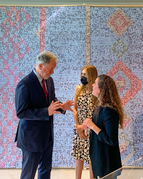 MIT Professor Sarah Williams discusses research with two World Food Program board members in front of a multi-colored tapestry. 
