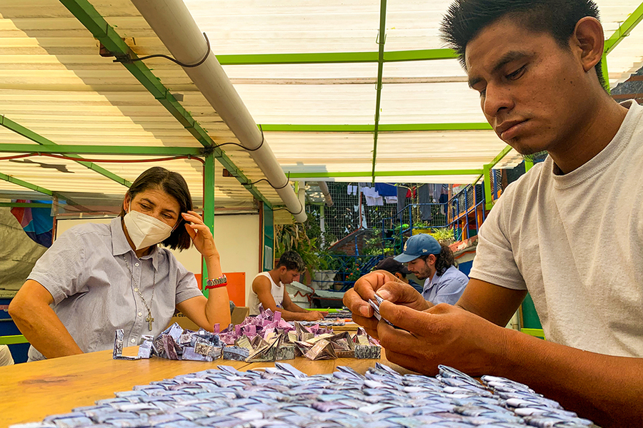 Four men and women, identified as migrants, weave tapestry for exhibition to illuminate the many stories behind migrant journeys.