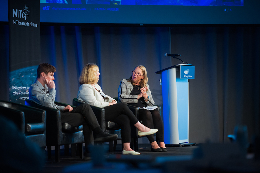Three people sit on a stage talking to each other during a panel.