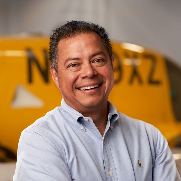 Portrait photo of Leon Villegas with a yellow Wisk Aero aircraft in the background