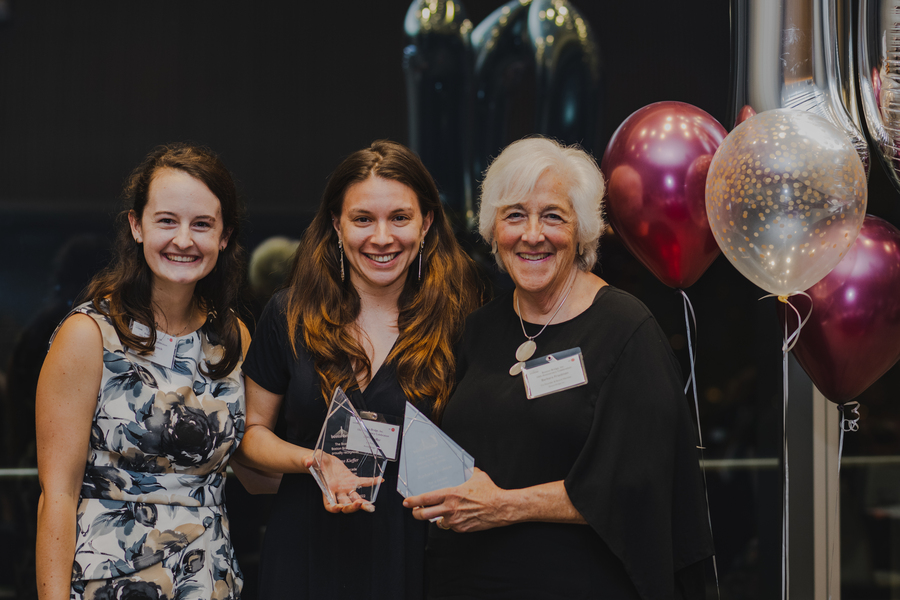 Taylor Patskanick, Barbara Friedman, and Elana Kieffer pose for a photo at a party. Several balloons are seen in the background.