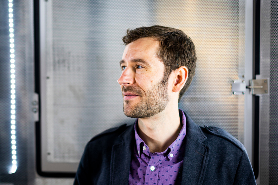 James LeBeau looks to the side, with large metallic reflective devices in background.