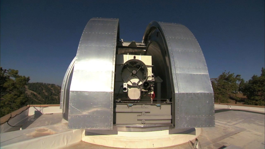 A large metal dome encloses a one-meter telescope, pictured against a clear, deep blue sky