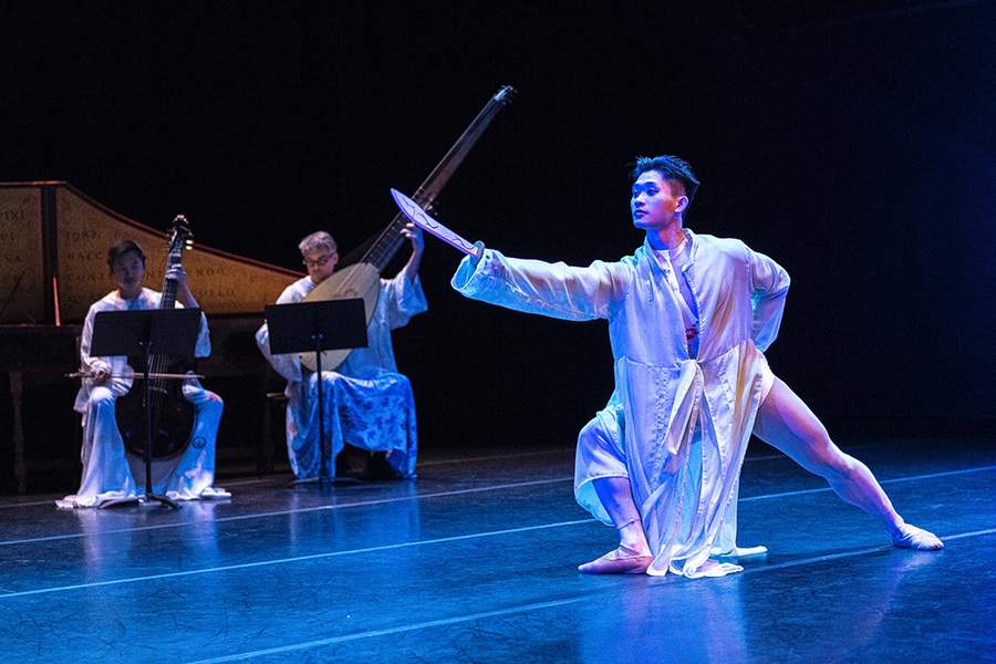 Ballet dancer holding a sword with musicians in background