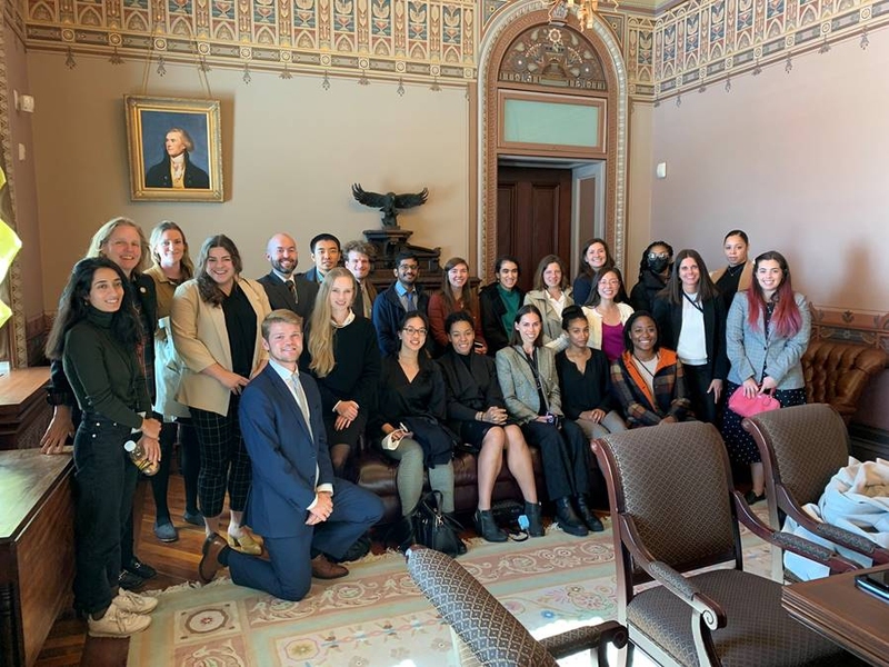 A group of MIT students dressed in suits pose in an ornate room